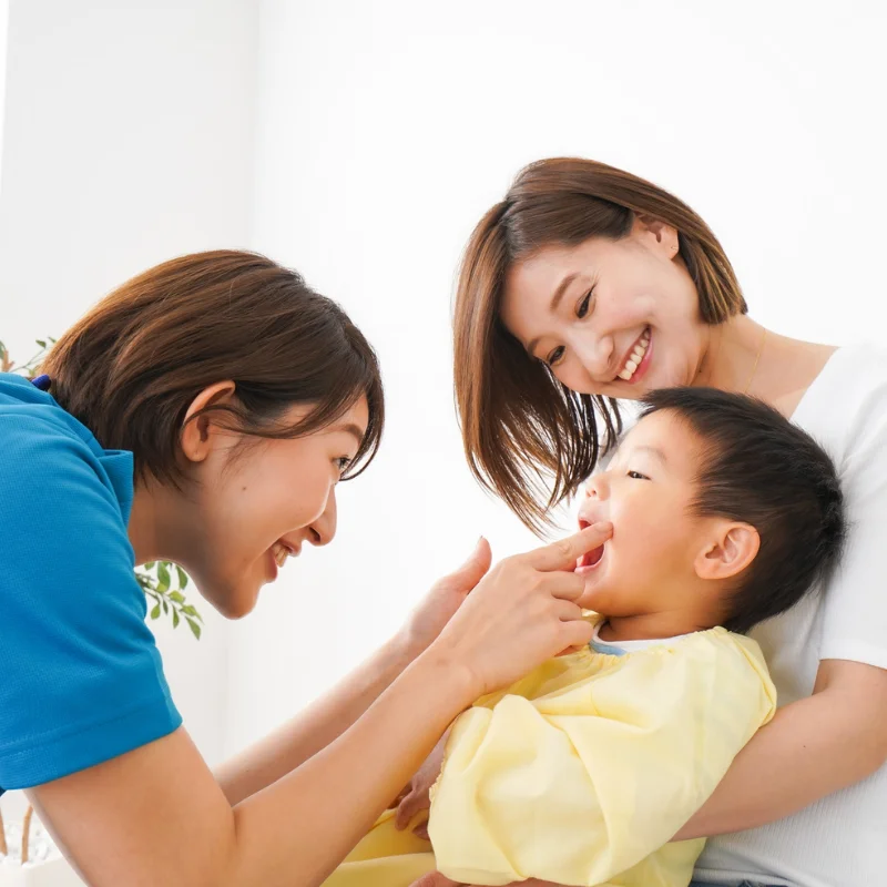 Dentist checking a young child’s teeth while the mother holds the child during a pediatric dental visit at Riverfront Dental in Cambridge Ontario