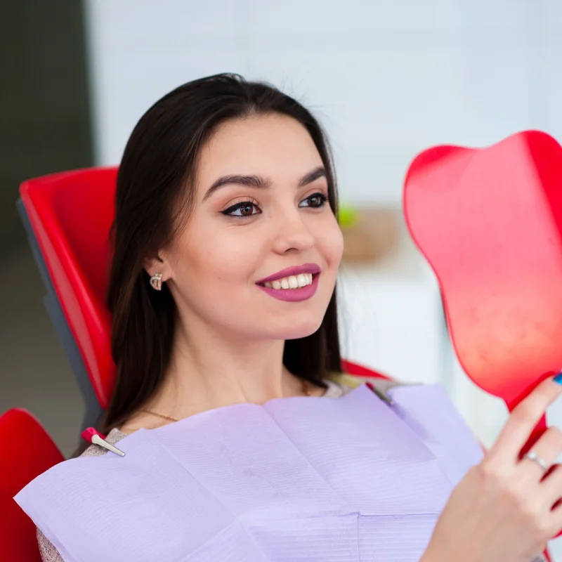 Female patient checking her smile after cosmetic dental treatment at Riverfront Dental in Cambridge Ontario