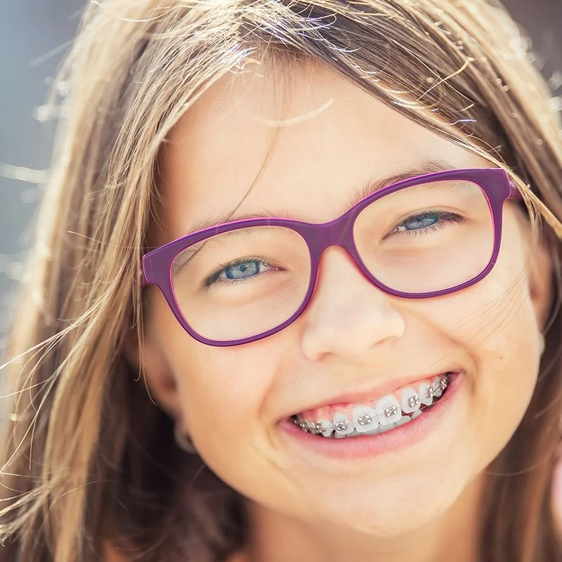 Smiling child wearing orthodontic braces showing results of orthodontic treatment at Riverfront Dental in Cambridge Ontario