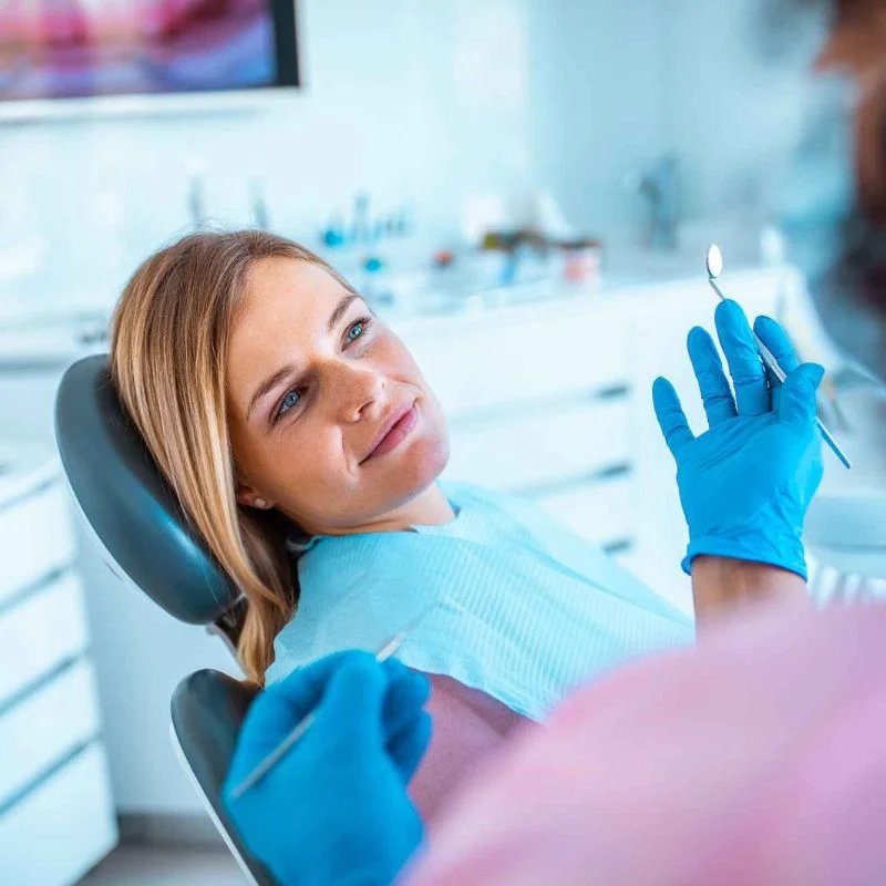 Patient sitting in a dental chair while a dentist prepares tools for a wisdom teeth examination at Riverfront Dental in Cambridge Ontario