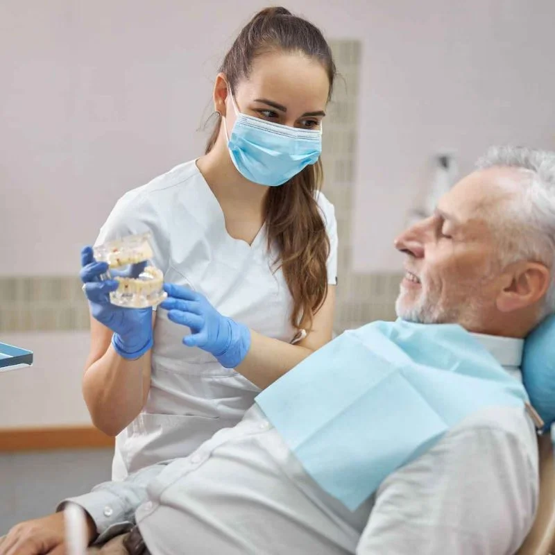 Dentist showing a denture model to an older patient during a denture consultation at Riverfront Dental in Cambridge Ontario