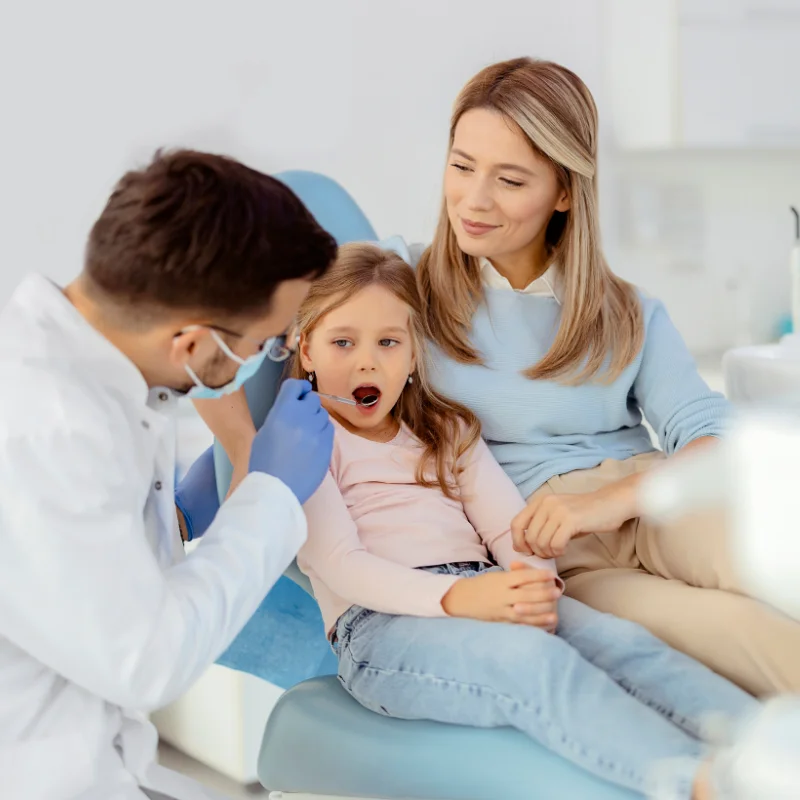 Dentist examining a young child’s teeth while the parent sits nearby during a family dental appointment at Riverfront Dental in Cambridge Ontario