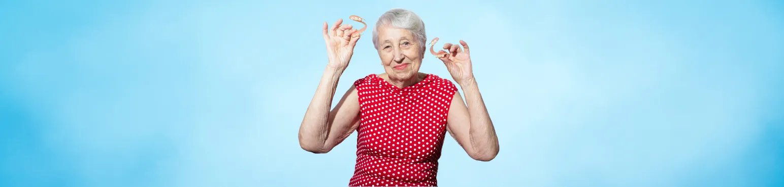 Dentures and Tooth Replacement Services at Riverfront Dental Cambridge ON Senior woman holding removable dentures and smiling, representing denture treatment at Riverfront Dental in Cambridge ON