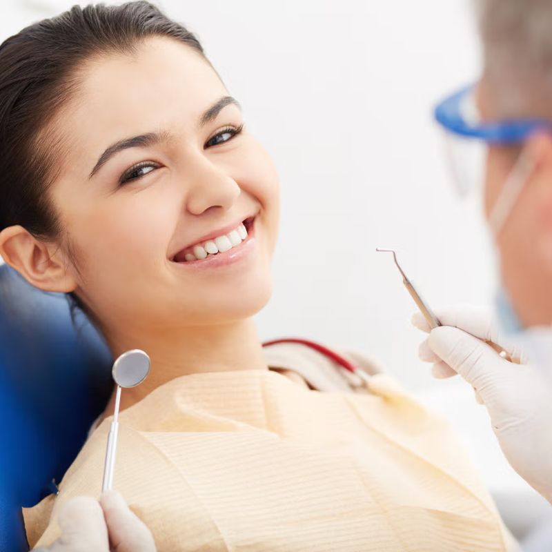 Smiling patient sitting in a dental chair while a dentist prepares tools for endodontic treatment at Riverfront Dental in Cambridge Ontario
